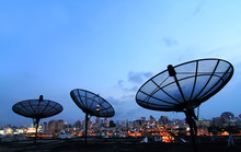 Black Antenna Communication Satellite Dish Over Sunset Sky In Ci