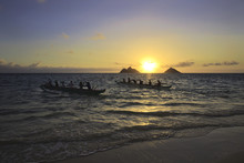 Outrigger Canoes Paddle Out From Shore At Sunrise