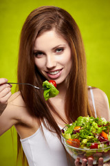 Healthy lifestyle - woman holding vegetable salad on green backg