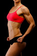 © Nobilior - Muscular female body against black background.