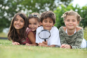 Kids playing with magnifying glass in park