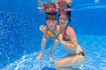 Underwater smiling family having fun in swimming pool