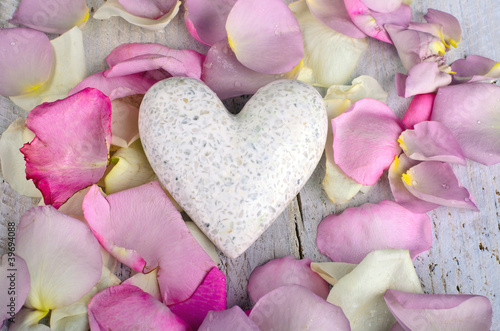 Fototapeta na wymiar White marple heart with rose petals on wooden background