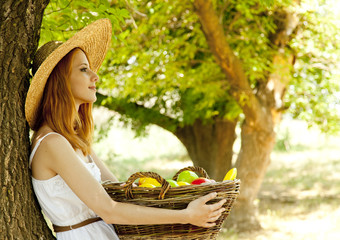 Wall Mural - Beautiful redhead girl with fruits in basket at garden.