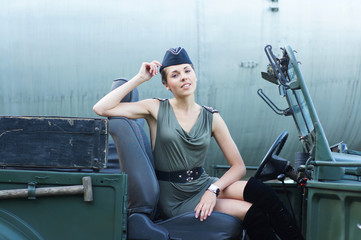 A young Caucasian woman driving a military car