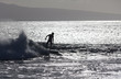 surfer silhoutted against the silver waves on maui coast
