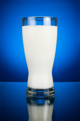 Wall Mural - Glass of fresh milk on a dark blue background