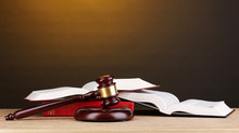 Judge's Gavel And Books On Wooden Table On Brown Background
