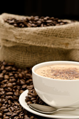 Cup of cappucino arranged with coffee beans and bag