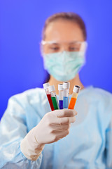 Canvas Print - Doctor (woman) analyzing medical test tubes on blue background