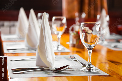 Naklejka dekoracyjna Glasses and plates on table in restaurant