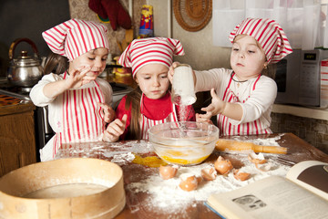 Three little chefs enjoying in the kitchen making big mess. Litt