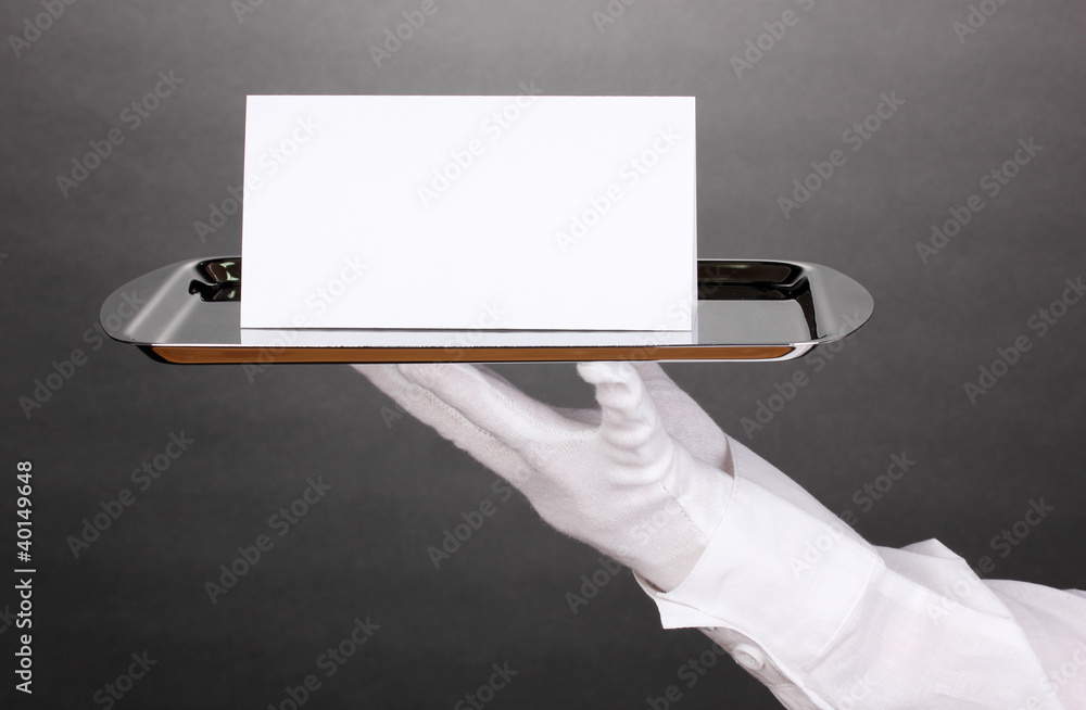 Hand in glove holding silver tray with blank card