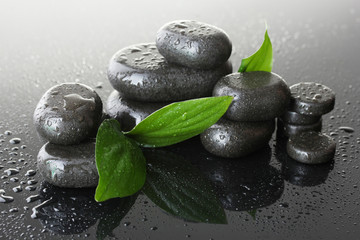 Poster - Spa stones with drops and green leaves on grey background