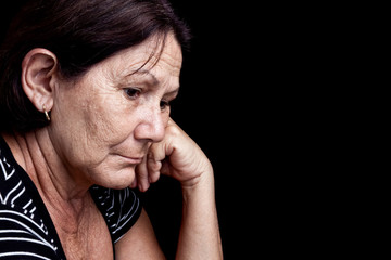 Wall Mural - Sad and worried old woman isolated on black