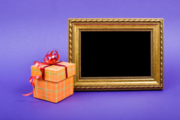 Gold photo frame and orange gift box with red ribbon on blue bac