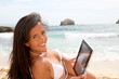 © goodluz - Beautiful woman in bikini using tablet on the beach