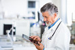 © lightpoet - Senior doctor using his tablet computer at work