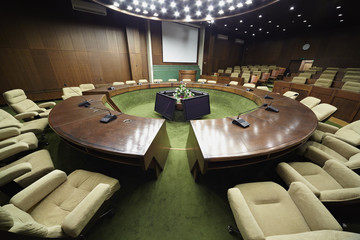 Auditorium with round oak table and beige armchairs around it