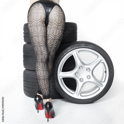 Nowoczesny obraz na płótnie Sexy woman with High Heels playing with set of summer tyres