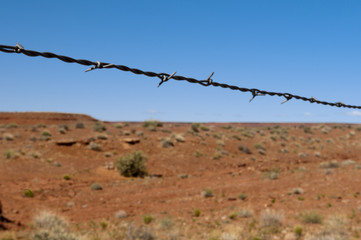 barbed wire as divider to the hot red desert with blue sky