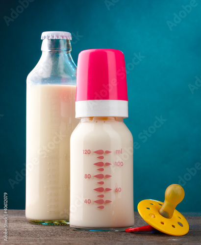 bottles of milk and soother on wooden table on blue background Fototapeta