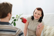 © Alliance - Young man presenting red rose to girlfriend