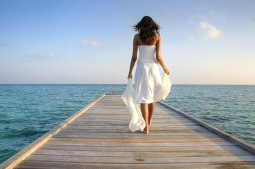 Sexy happy woman in white clothes standing on a jetty (Maldives)