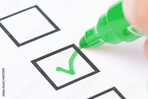 Fotografie, Obraz Macro shot of human hand drawing green check mark in checklist b