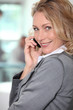 © auremar - Blond businesswoman taking a call whilst stood in the office