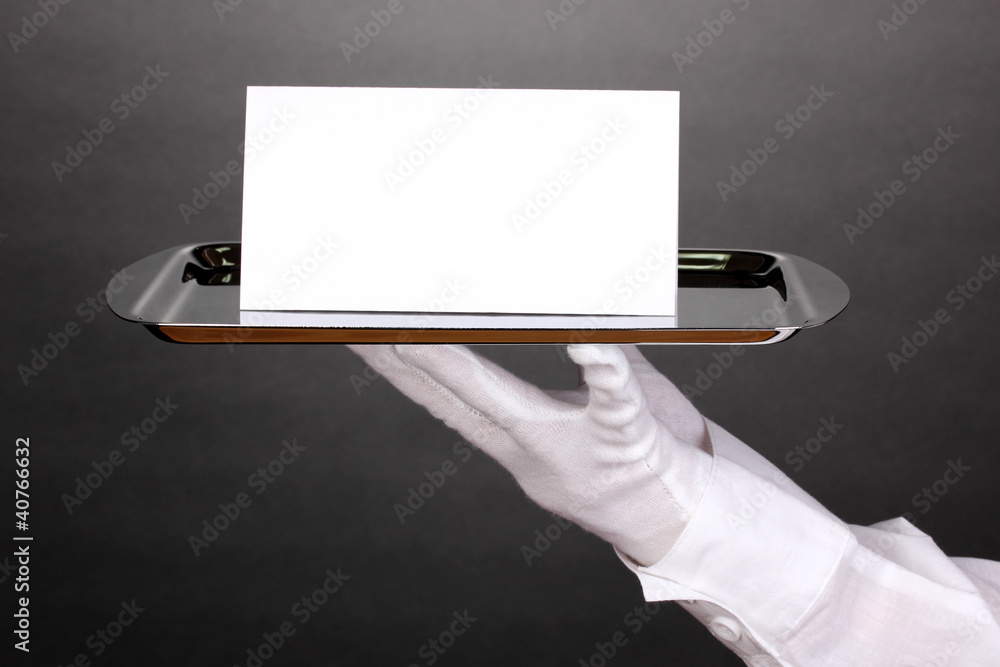 Hand in glove holding silver tray with blank card