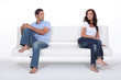 couple sitting apart in couch after quarrel