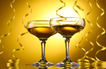 glasses of champagne and streamer on yellow background