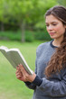 © WavebreakmediaMicro - Young relaxed girl reading a book in a park