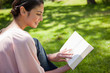 © WavebreakmediaMicro - Woman reading a book while sitting in the grass