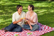 © WavebreakmediaMicro - Two friends laughing while raising their glasses during a picnic