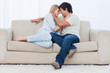 © WavebreakmediaMicro - A couple are sitting on a couch looking at each other with their