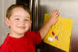 © Robert Hainer - Child putting his art up on family refrigerator at home