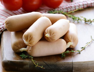 small fresh sausages on wooden board