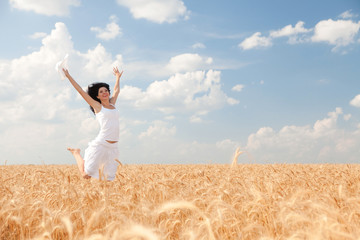 Happy woman jumping in golden wheat