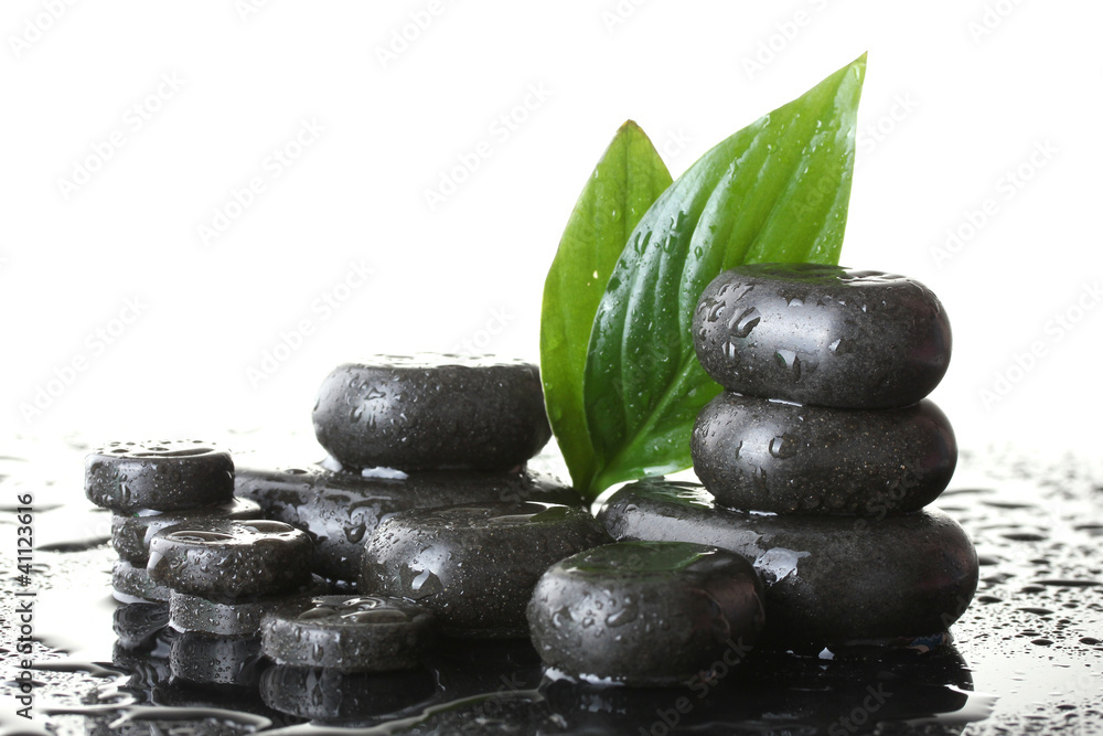 Spa stones with drops and green leaves on white background