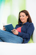 © Racle Fotodesign - junge frau liegt bequem auf der couch und liest ein buch