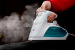 © Yurchyk - hand in red sleeve holding steaming iron