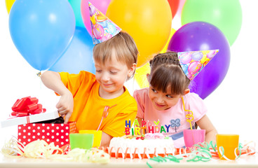 adorable children celebrating birthday party and opening gift bo