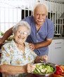 © Gustavo Andrade - Señores abuelos cocinando en una cocina.Comiendo ensalada.