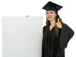 Wall Mural - Happy graduation student girl holding blank billboard