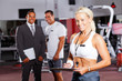 © michaeljung - happy female gym trainer portrait with colleagues in background