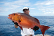 Happy  fisherman holding a beautiful red snapper