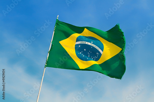 Fotografie, Obraz Brazil flag flutters against Brazilian blue skies