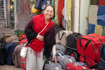 Sticker - woman chooses suitcase at  shop